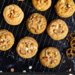 Salted Butterscotch Pretzel Cookies on a cooling rack on a dark surface.