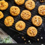 Salted Butterscotch Pretzel Cookies on a cooling rack on a dark surface.