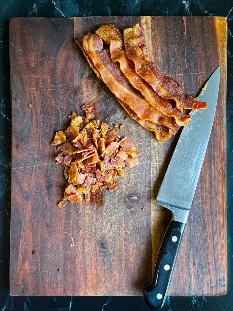 Bacon diced on a wooden cutting board.