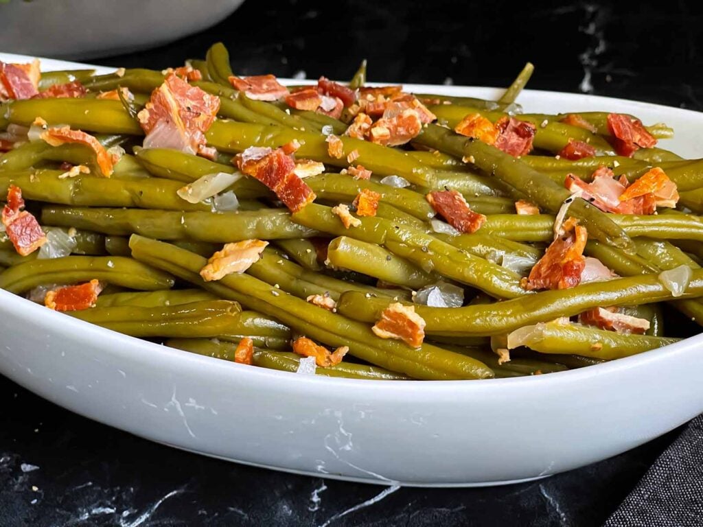 Southern slow cooker green beans in a light bowl on a dark surface.
