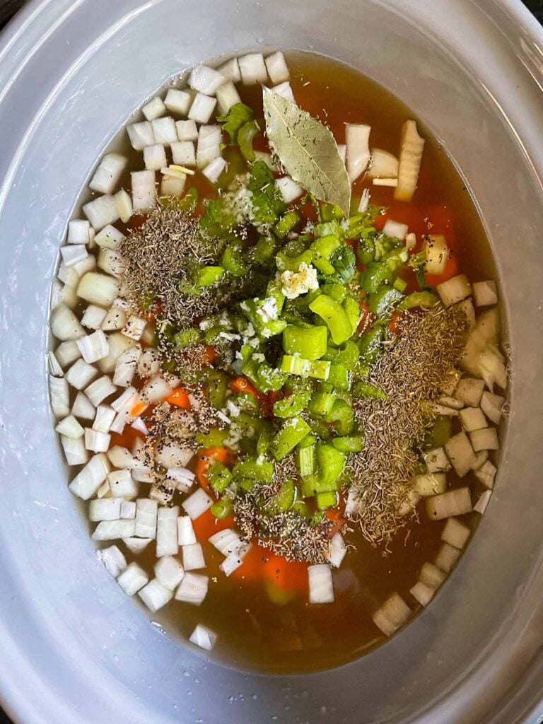 Ham and bean soup ingredients added to a slow cooker.