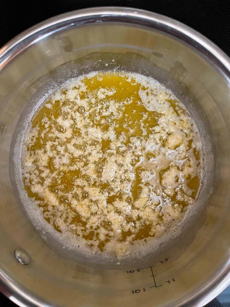 Butter with herbs with garlic just added in a sauce pan.