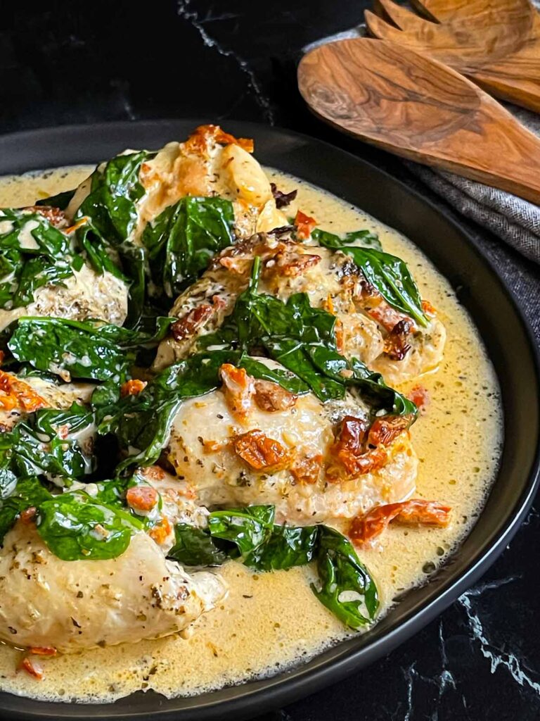 Slow Cooker Tuscan Chicken in a dark bowl on a dark surface.