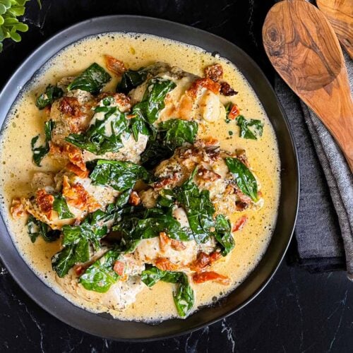 Slow Cooker Tuscan Chicken in a dark bowl on a dark surface.