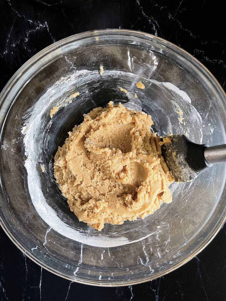 Snickerdoodle Bars dough mixed together in a large glass bowl on a dark surface.