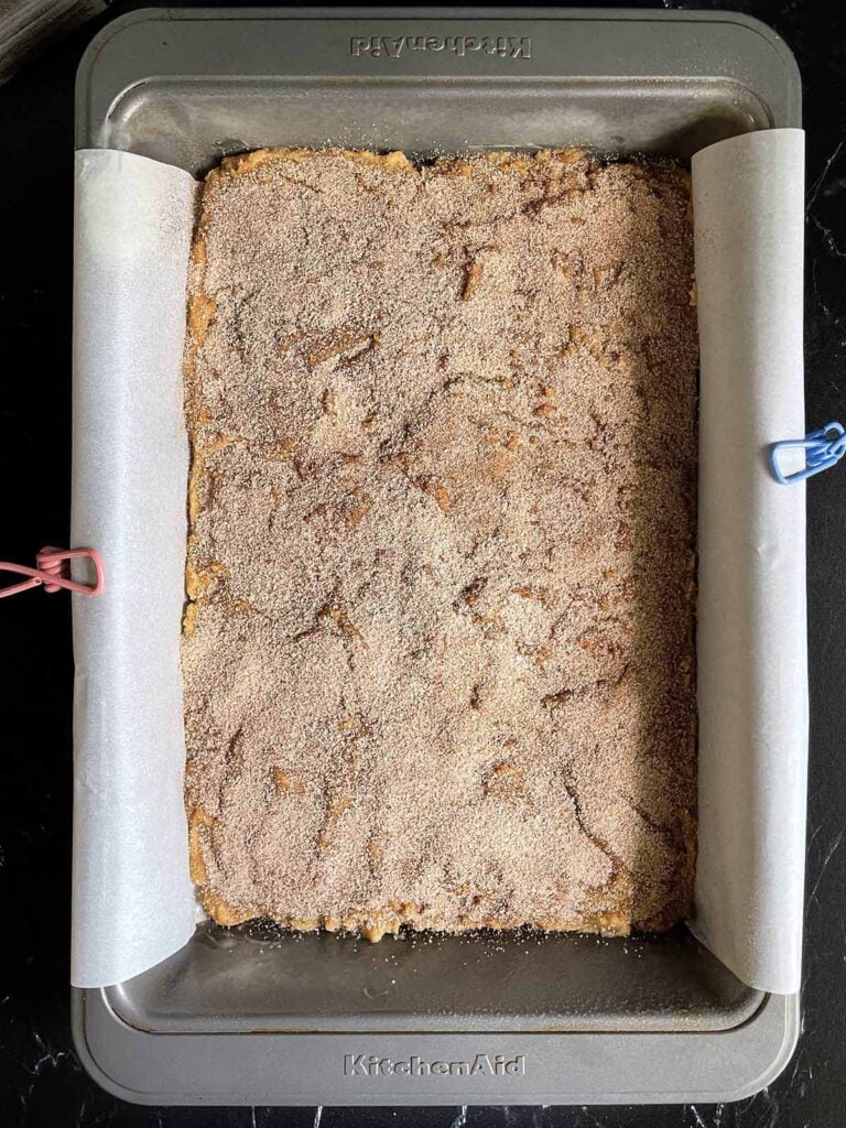 Unbaked Snickerdoodle Bars dough in the parchment paper lined baking pan.