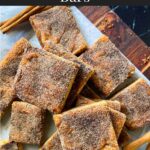 Snickerdoodle Bars stacked on a wooden cutting board.