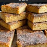 Snickerdoodle Bars stacked on a wooden cutting board.