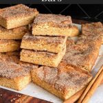 Snickerdoodle Bars stacked on a wooden cutting board.