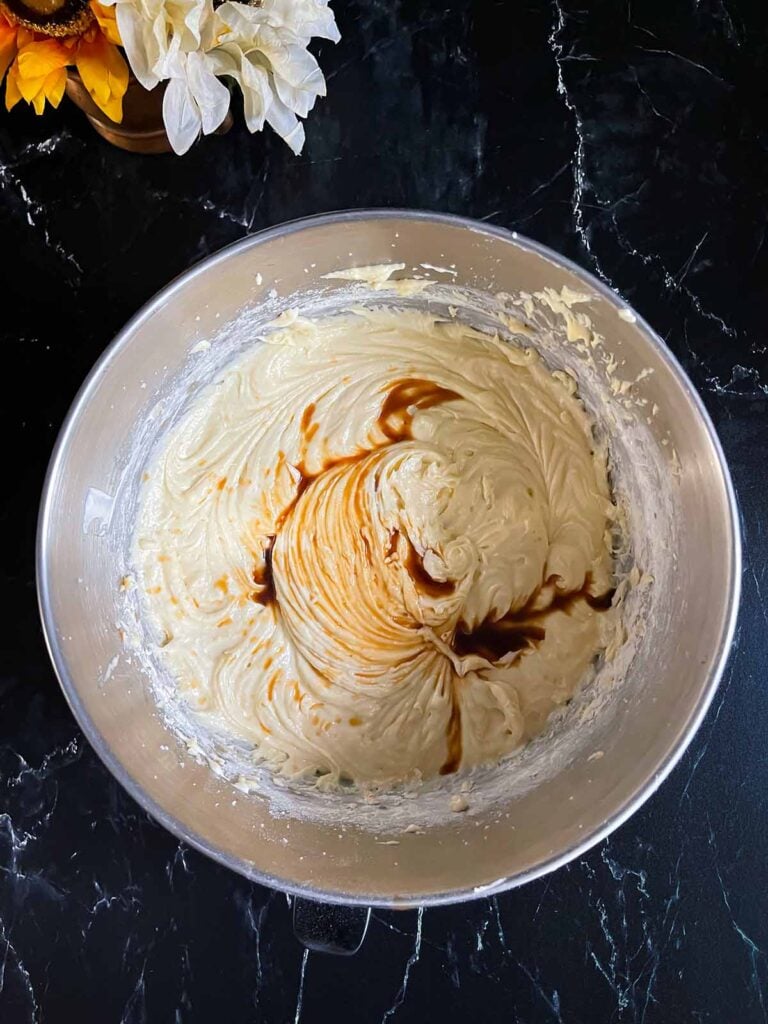 Adding vanilla to the ingredients for old fashioned sour cream pound cake in mixing bowls.