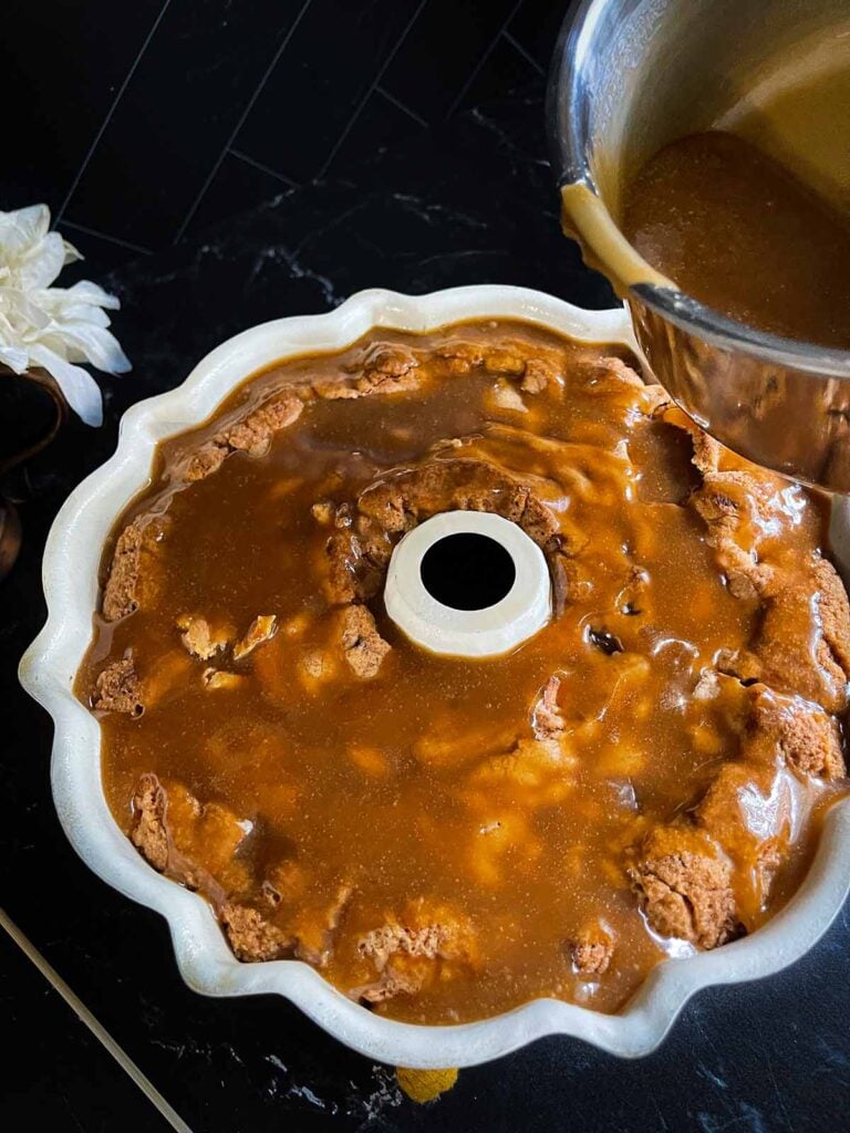 Caramel glaze poured over the apple dapple cake still in a bundt pan.