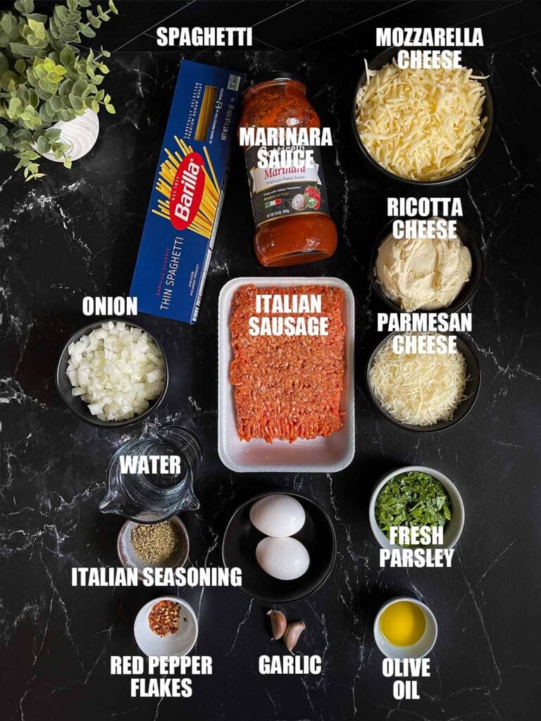 Baked spaghetti ingredients on a dark surface.
