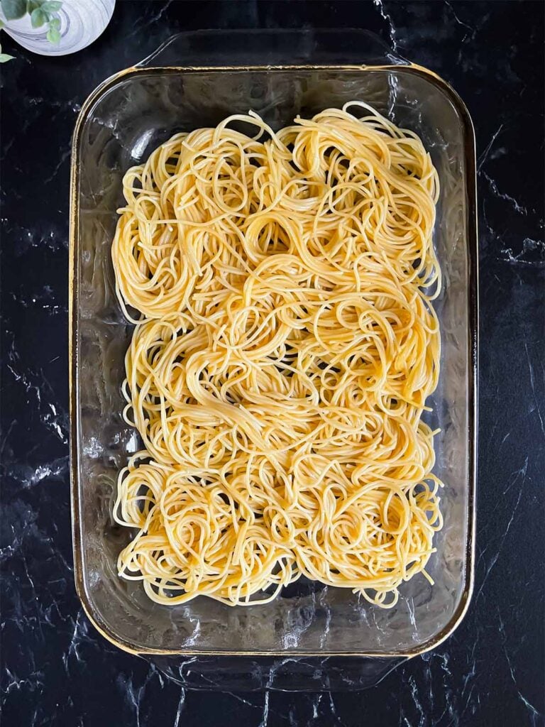 First layer of noodles in a glass baking pan for baked spaghetti.