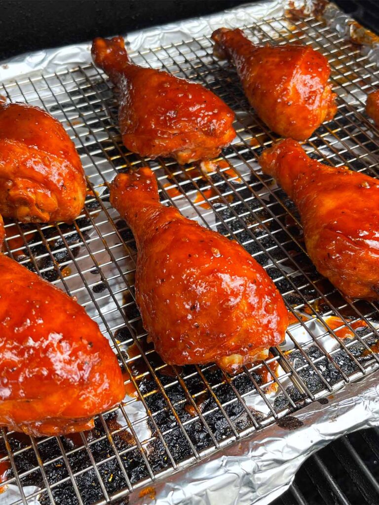 Chicken legs smoking on a smoker.