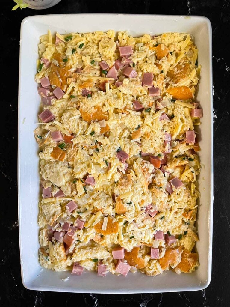 Unbaked ham and cheese strata in a baking dish.