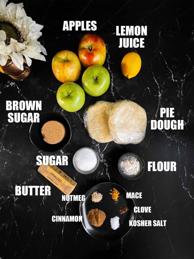 Ingredients for apple pie on a dark surface.