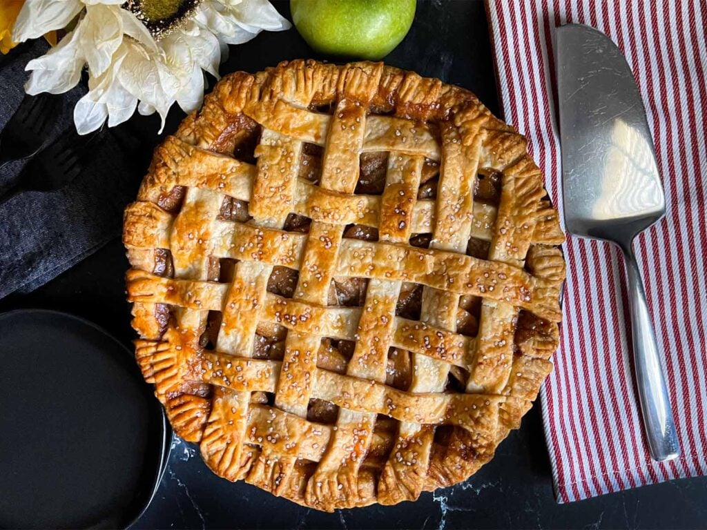 Lattice crust apple pie on a dark surface.