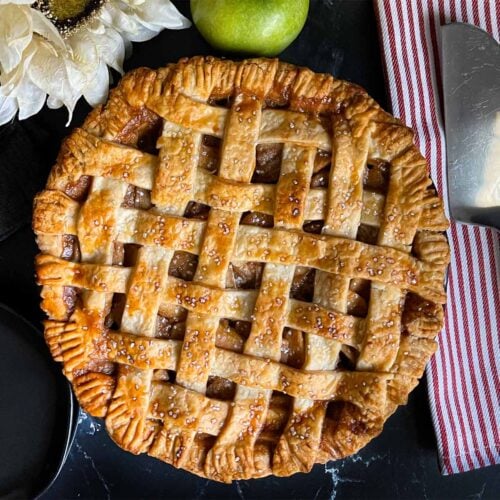 Lattice crust apple pie on a dark surface.