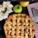 Lattice crust apple pie on a dark surface.