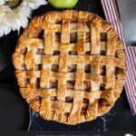 Lattice crust apple pie on a dark surface.