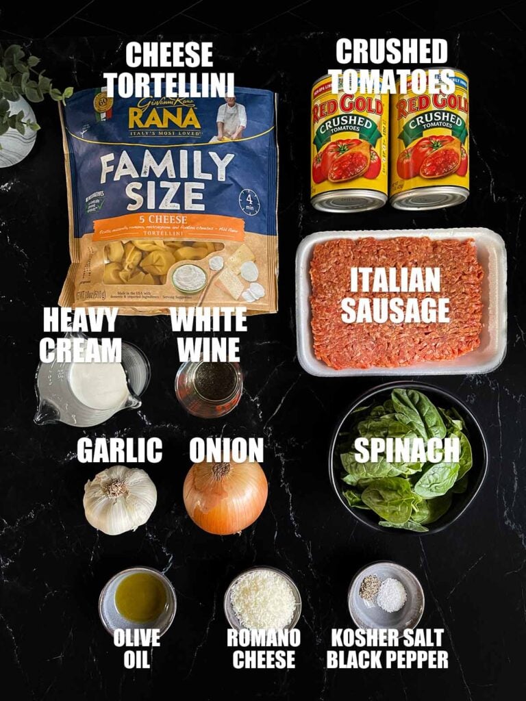 Ingredients for Tortellini with Sausage on a dark surface.