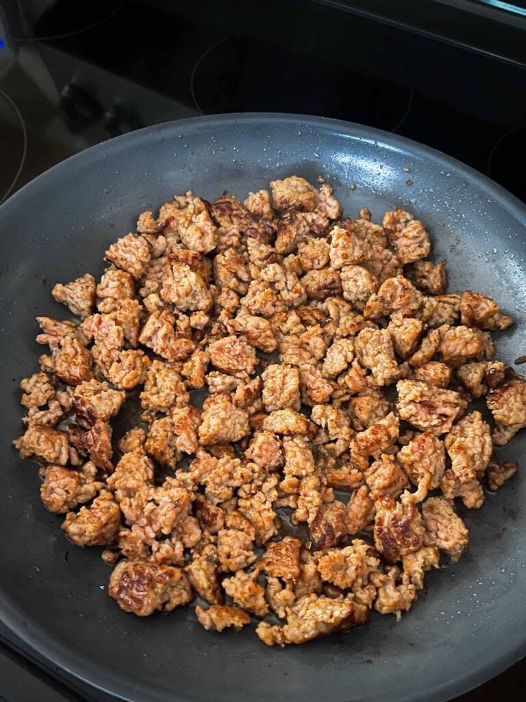 Browned italian sausage in a skillet.