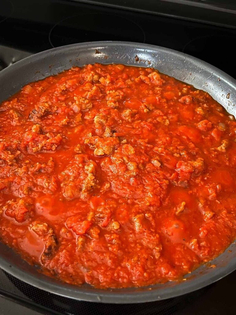 Tomato sauce with italian sausage simmering in a skillet