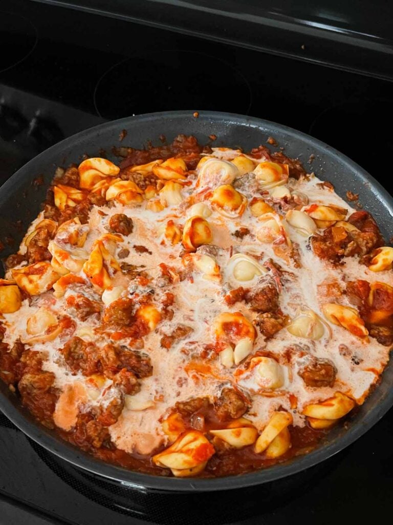 Cream added to a tortellini with italian sausage dish.