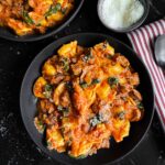 Tortellini with italian sausage and spinach in a dark bowl on a dark surface.