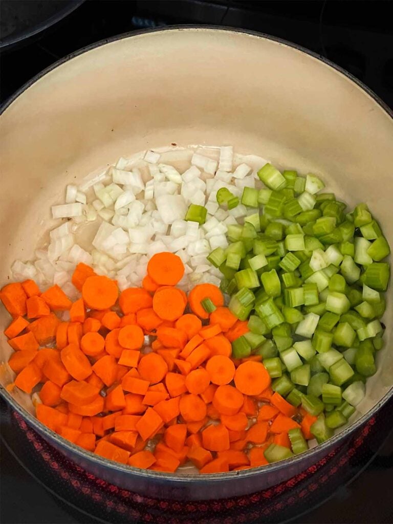 Onions, celery, and carrot just added to a dutch oven.