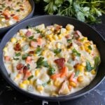 Potato corn chowder in a dark bowl on a dark surface.