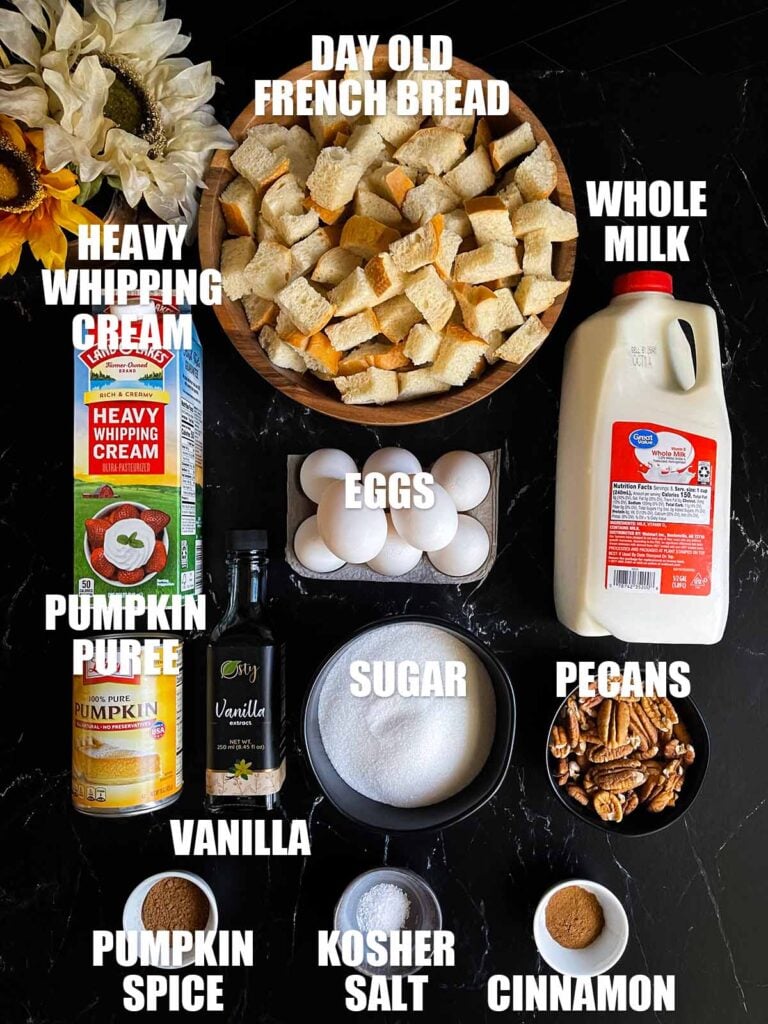 Ingredients for pumpkin bread pudding on a dark surface.