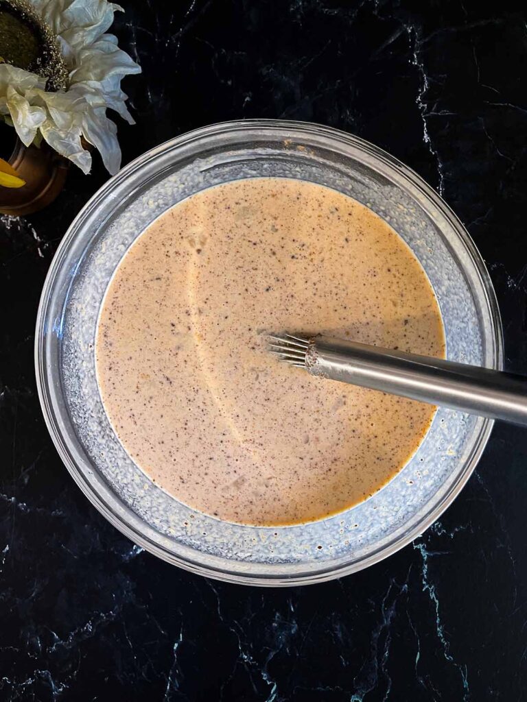 Custard ingredients mixed in a glass bowl for pumpkin bread pudding.