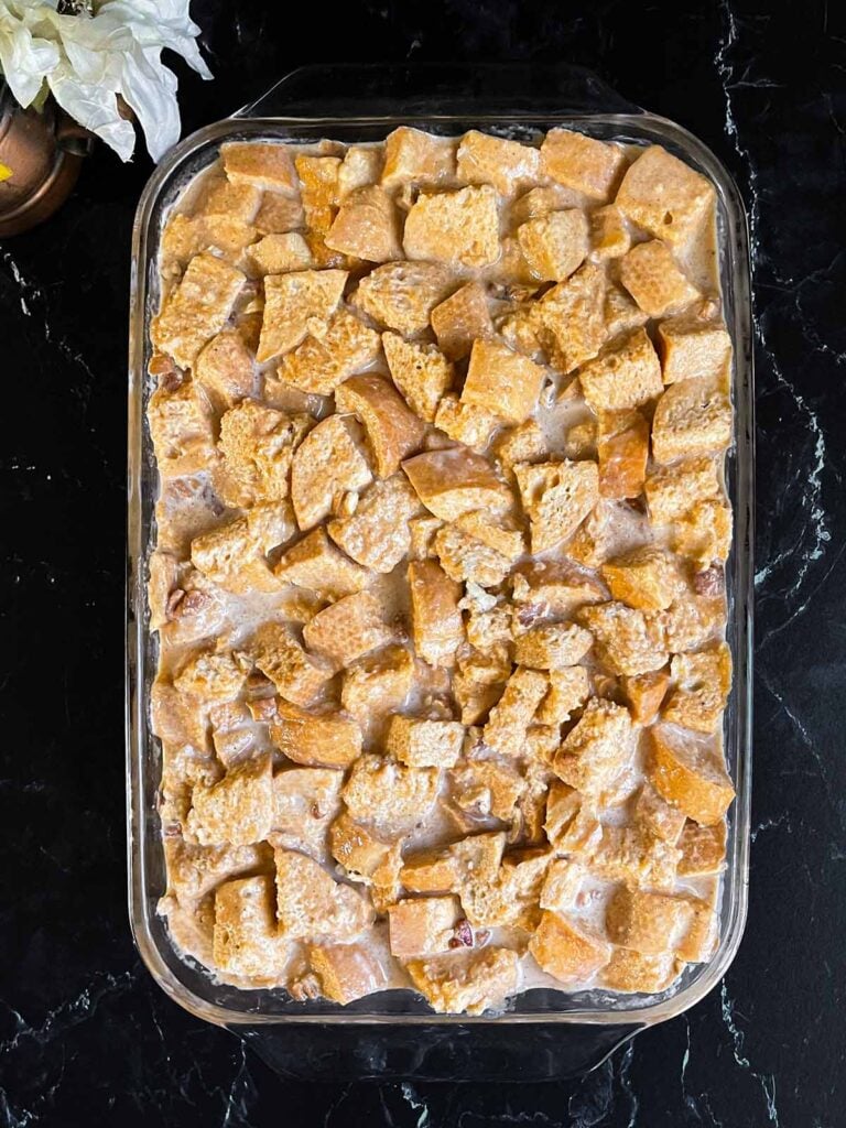 Unbaked pumpkin bread pudding in a 9x13 baking dish on a dark surface.