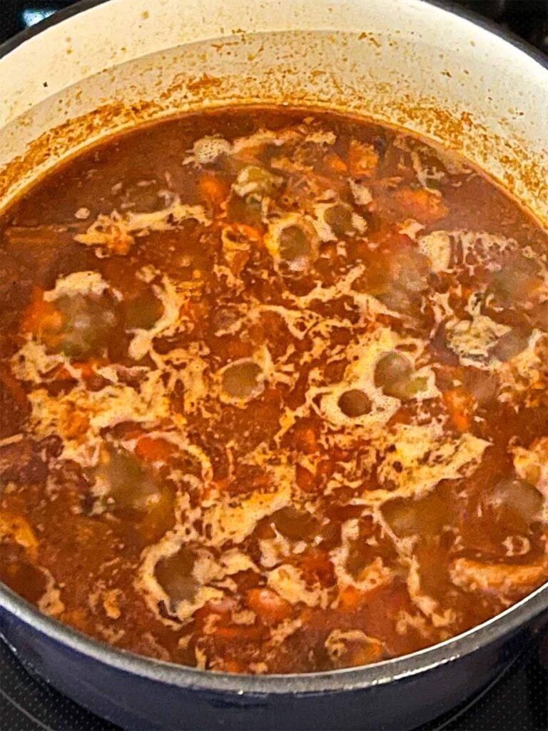 Smoked pork chili cooking in a dutch oven.