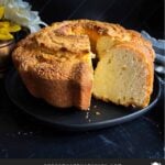 Pound cake on a black plate with one slice cut.