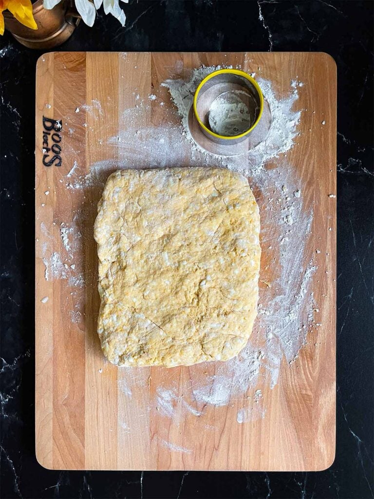 Sweet potato biscuit dough formed into a rectangle on a floured wooden board.