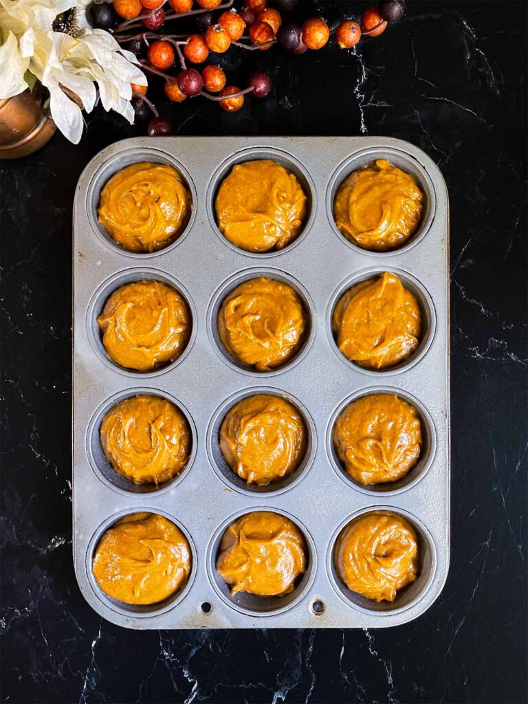 Sweet potato muffin batter divided into a 12 cup muffin tin.
