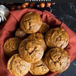 Sweet potato muffins in a cloth lined bread basket on a dark surface.