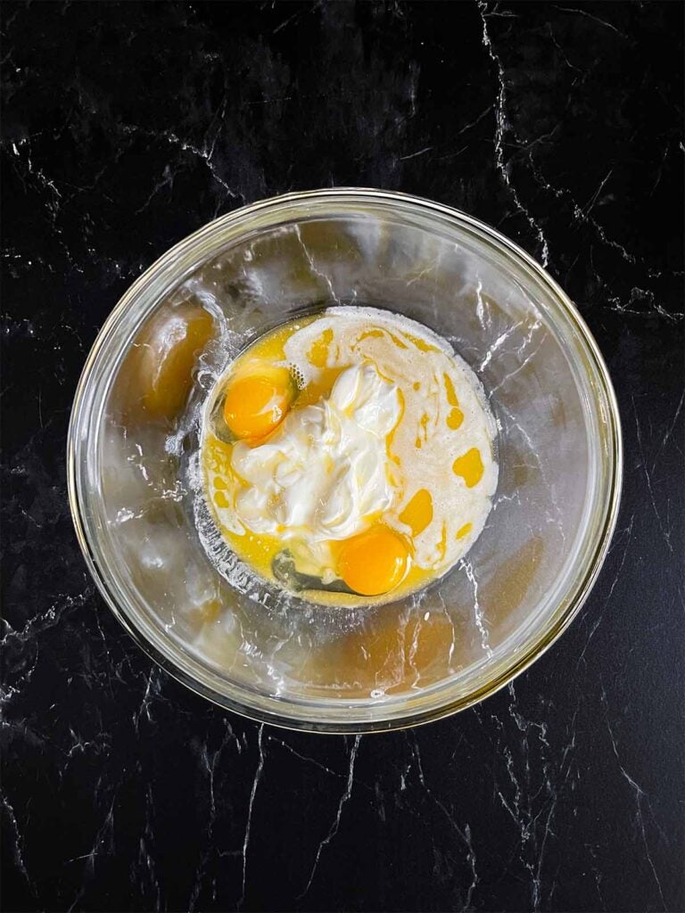 Corn casserole wet ingredients in a glass bowl.