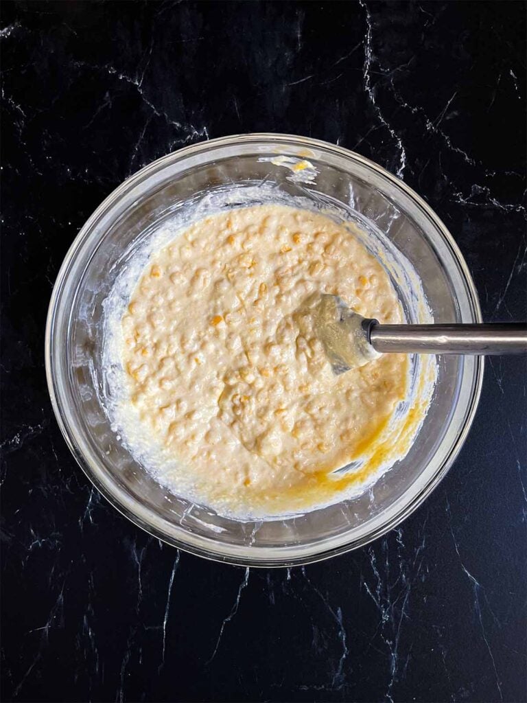 Corn casserole batter mixed in a glass mixing bowl.