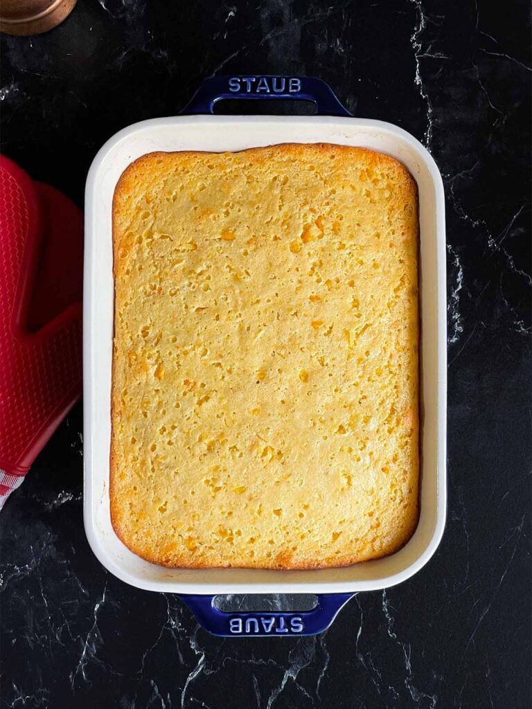 Baked corn casserole on a dark surface.