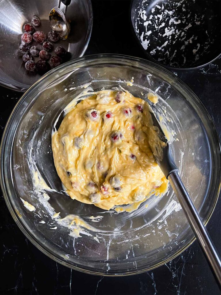 Ingredients for cranberry orange bread combined in a glass bowl.