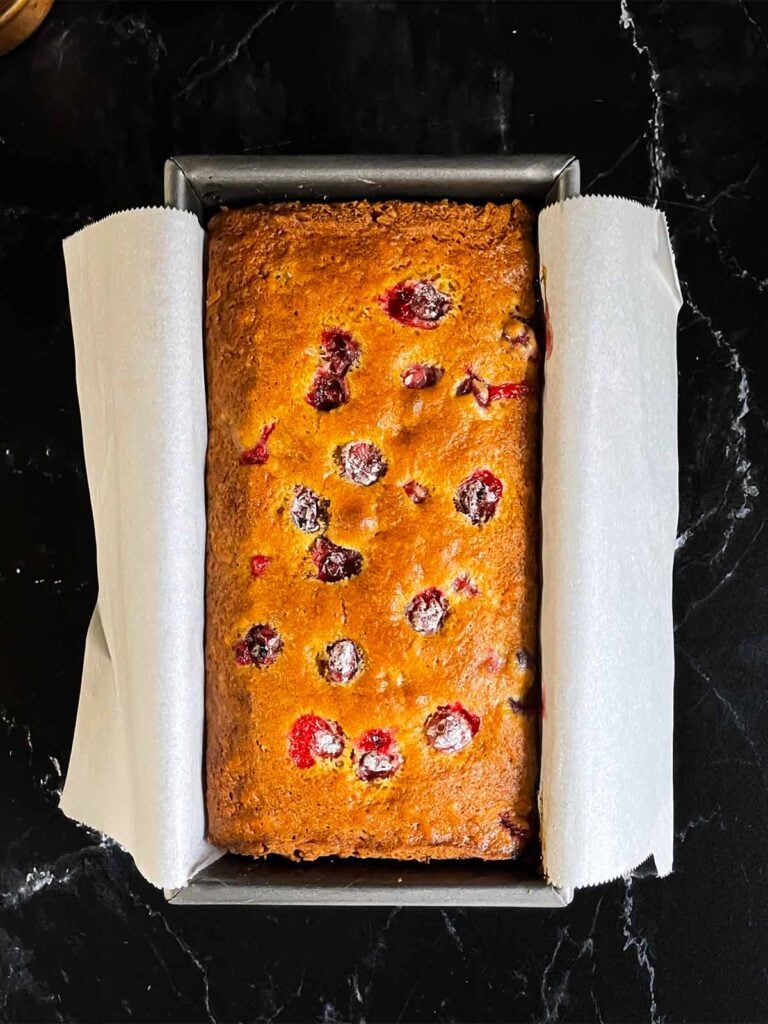 Cranberry orange bread fresh out of the oven in a loaf pan.