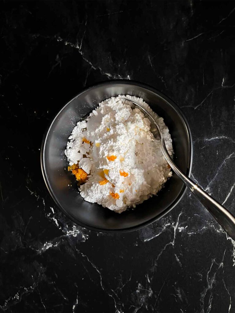 Orange glaze ingredients in a dark bowl on a dark surface.