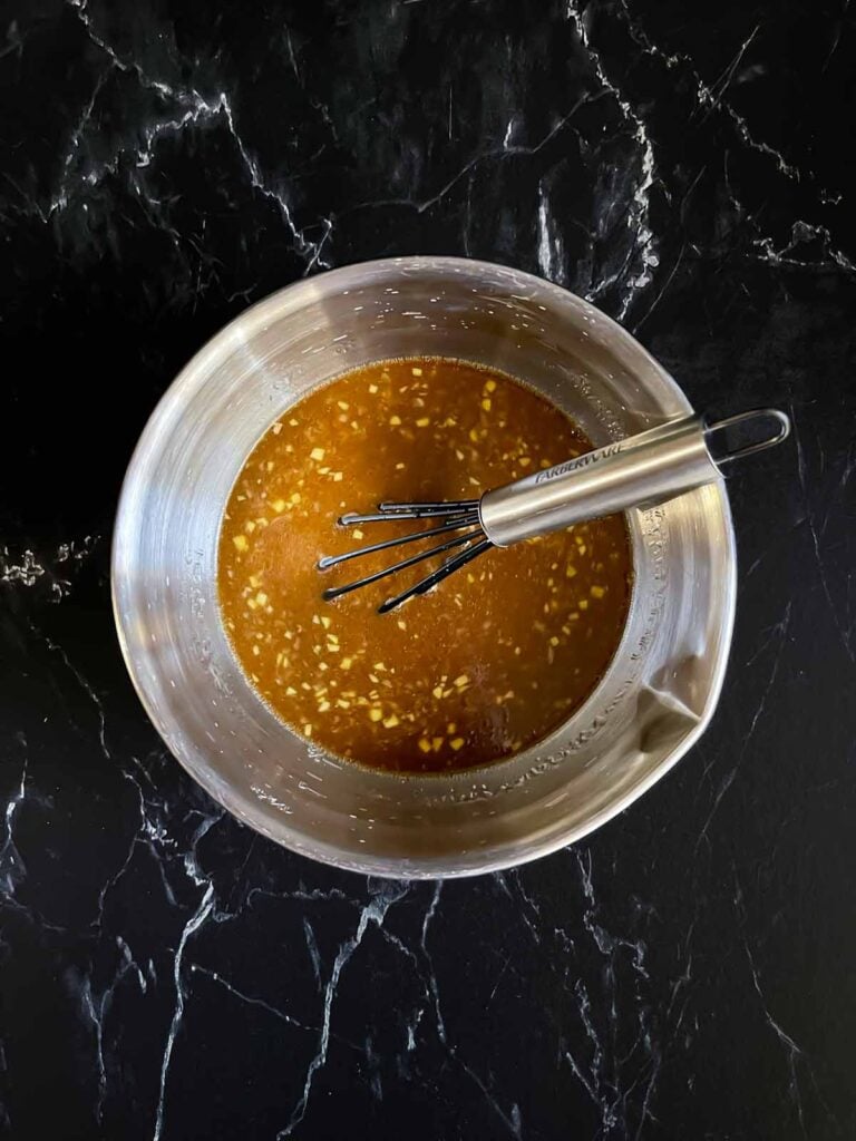 Chicken teriyaki marinade in an aluminium bowl on a dark surface.