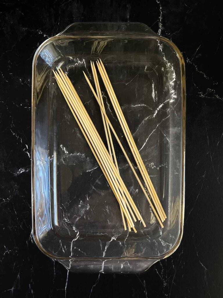 Bamboo skewers soaking in a water bath.