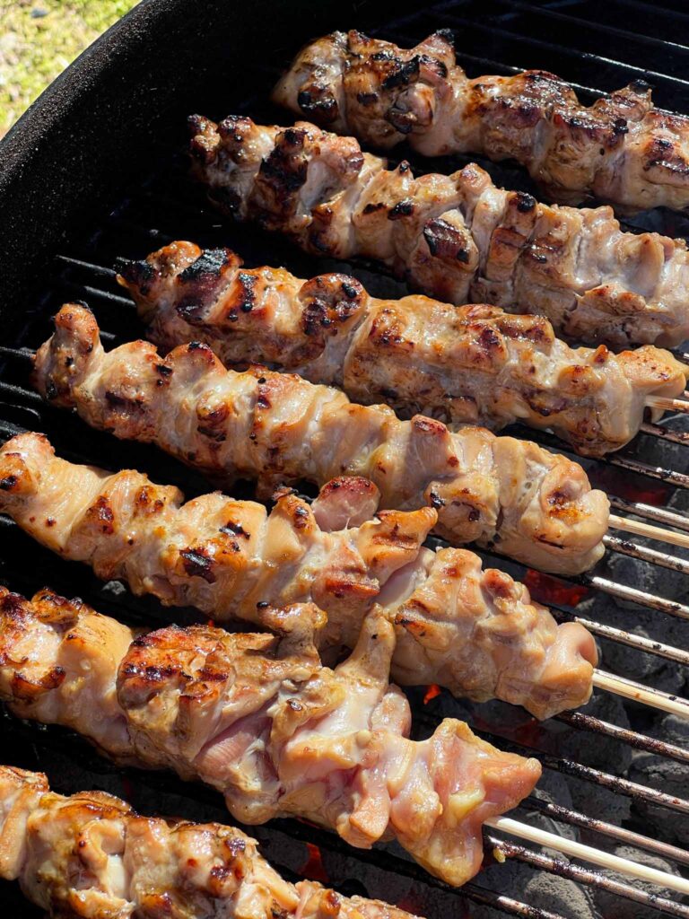 Chicken skewers starting to get some color on a Weber grill.