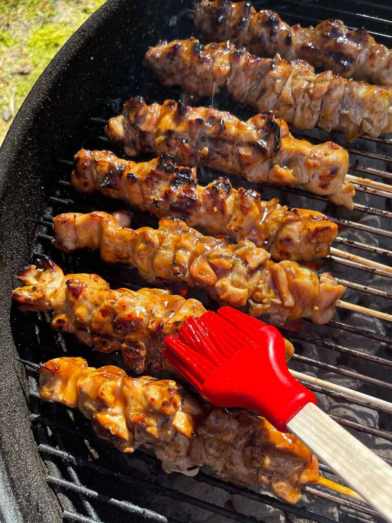 Basting chicken teriyaki skewers on a Weber grill.