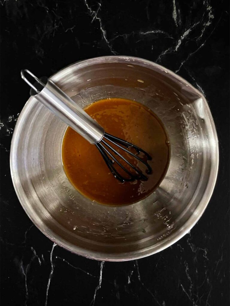 Sauce for lo mein in a mixing bowl on a dark surface.